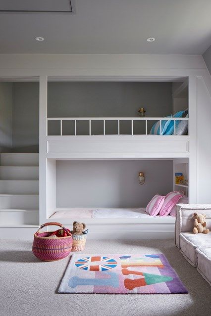 a minimalist shared girls' bedroom with bunk beds and built in shelves, a sofa by the window and bright printed textiles a minimalist shared girls' bedroom with bunk beds and built-in shelves, a sofa by the window and bright printed textiles