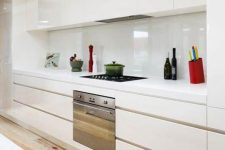 a modern creamy kitchen with sleek cabinets, white stone countertops and a white creamy backsplash for a catchy glossy touch