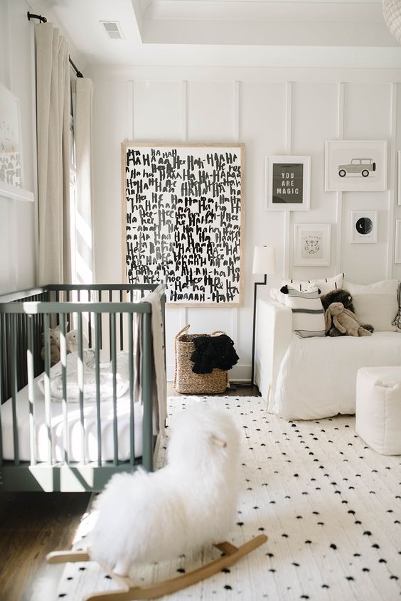 a monochromatic nursery with printed textiles and a graphic artwork, neutral and green furniture and paneling on the wall