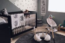 a monochromatic zoo inspired nursery with a cool crib, a black dresser, lovely kid’s facilities, an accent wall and animal plush toys