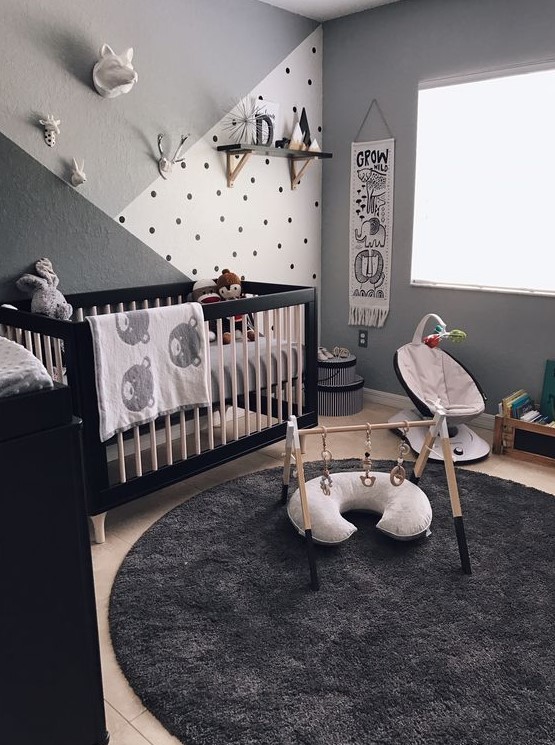 a monochromatic zoo inspired nursery with a cool crib, a black dresser, lovely kid's facilities, an accent wall and animal plush toys