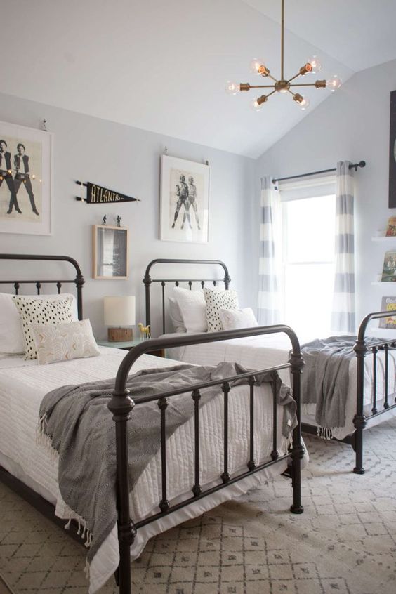 a neutral attic shared boy bedroom with metal beds, a gallery wall and a chandelier is a chic space