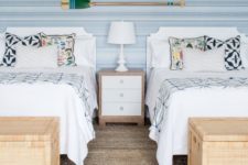 a neutral beach shared bedroom with two beds, wicker chests for storage and oars on the wall