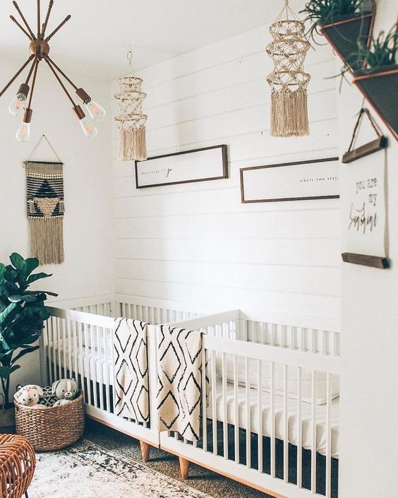 a neutral boho nursery with neutral furniture, printed linens, artworks and crochet chandeliers, a statement plant and touches of rattan