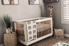 a neutral jungle-themed nursery with wooden furniture, layered rugs, an open shelf and a gallery wall