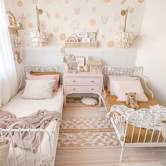 a pastel boho shared bedroom with metal beds, pastel and mustard bedding, boho rugs, a pink dresser and tassel pendant lamps a pastel boho shared bedroom with metal beds, pastel and mustard bedding, boho rugs, a pink dresser and tassel pendant lamps