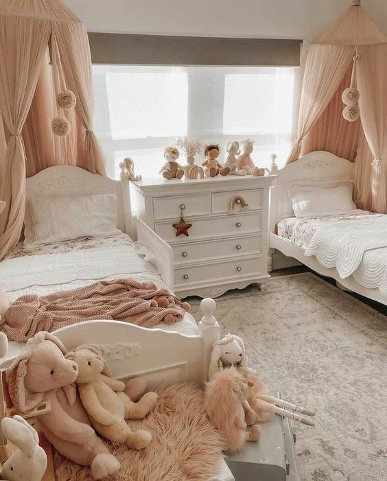 a pastel shared girls' bedroom with a grey accent wall, white vintage beds, pink and white bedding, a white vintage dresser, neutral and pastel toys