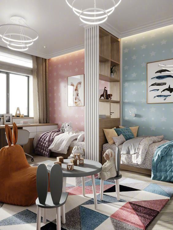 a pretty modern pastel shared girls' bedroom with a blue and a pink accent wall, a shelving unit that divides the sleeping space, desks by the window a pretty modern pastel shared girls' bedroom with a blue and a pink accent wall, a shelving unit that divides the sleeping space, desks by the window
