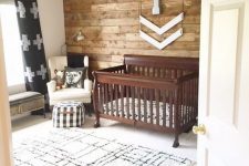 a rustic nursery with a printed rug, a stained crib, a reclaimed wall and some touches of prints