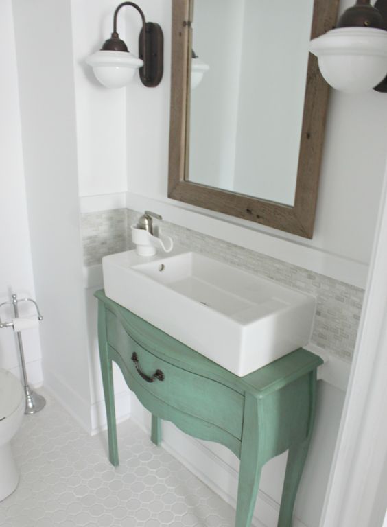 a small green brushed nightstand used as a creative and cool sink stand in a bathroom with a rustic and farmhouse feel