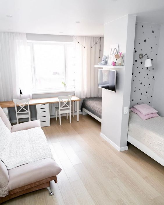 a small shared kids' bedroom with beds by the walls and a space divider, a double desk with chairs and a sofa plus a TV a small shared kids' bedroom with beds by the walls and a space divider, a double desk with chairs and a sofa plus a TV