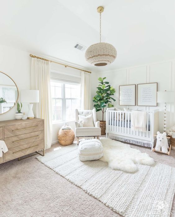 a soft and modern nursery with white walls and woodland decor and touches of boho is a gorgeous space