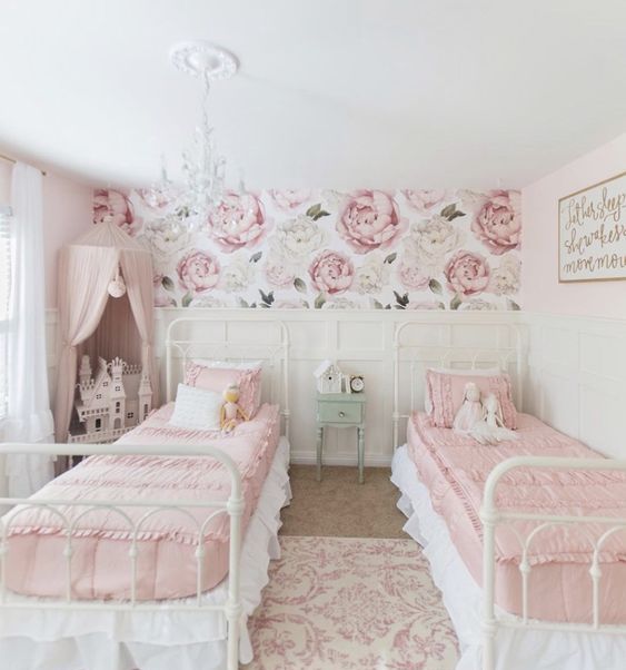 a sophisticated shared girls' bedroom with white metal beds, pink and white bedding, white paneled walls, a pink canopy over a doll house a sophisticated shared girls' bedroom with white metal beds, pink and white bedding, white paneled walls, a pink canopy over a doll house