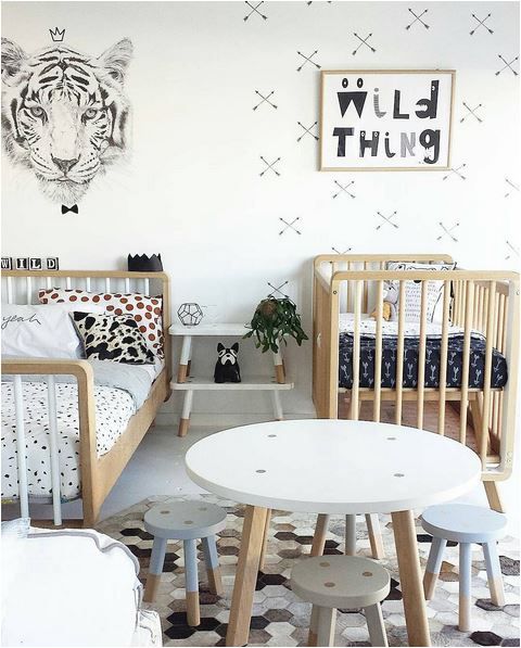 a stylish Scandinavian shared room done in black and white, with wooden furniture, pastel tbles and lots of prints