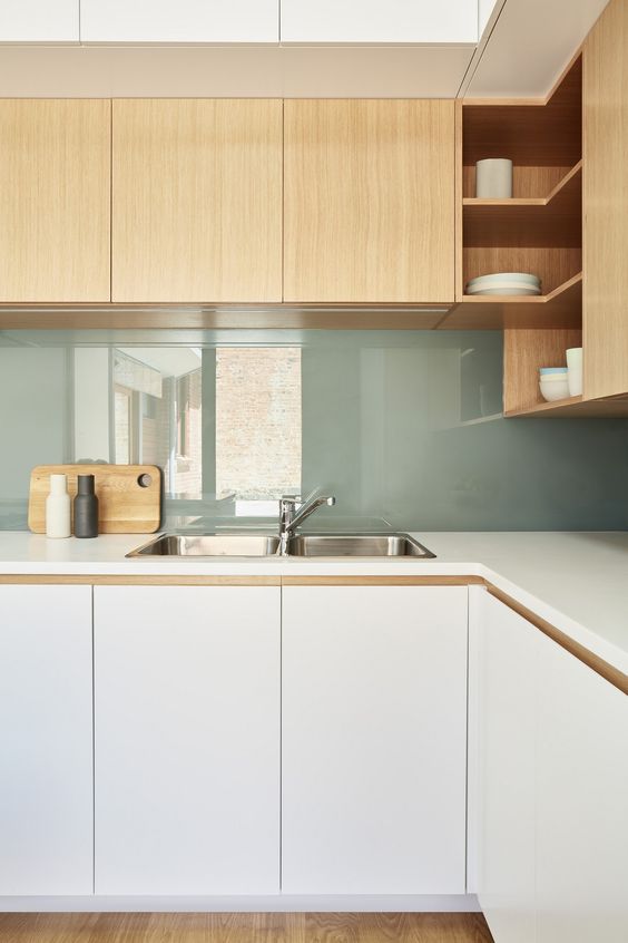 a stylish modern two-tone kitchen with sleek white and light-stained cabinets plus a green glass backsplash for a dainty touch of color