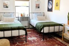 a stylish shared teen bedroom with metal beds, gallery walls, a printed rug and a wicker ottoman