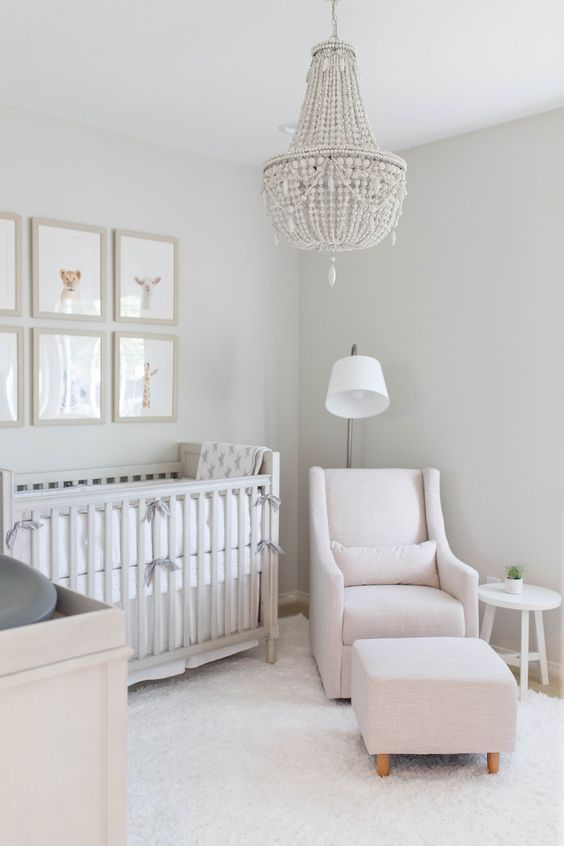 a totall neutral nursery with neutral furniture, a beaded chandelier, a gallery wall and pretty neutral textiles