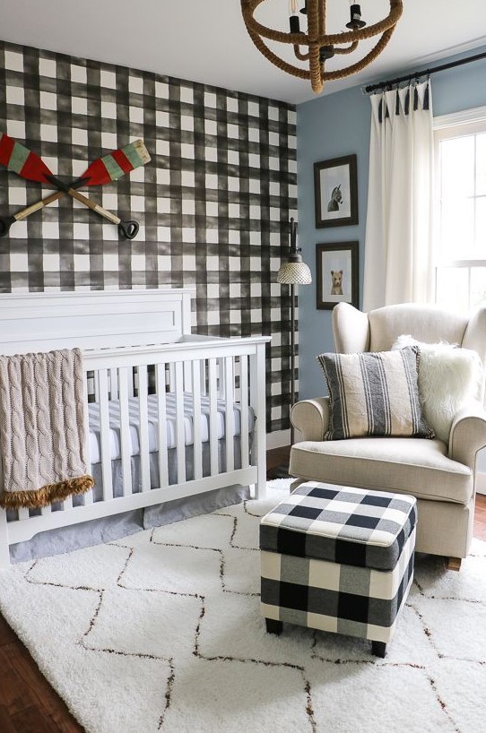 a welcoming farmhouse nursery with a plaid statement wall and a matching ottoman, neutral furniture and a unique sphere chandelier