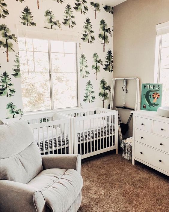 a woodland shared nursery with a tree statement wall, white furniture, artworks and much natural light