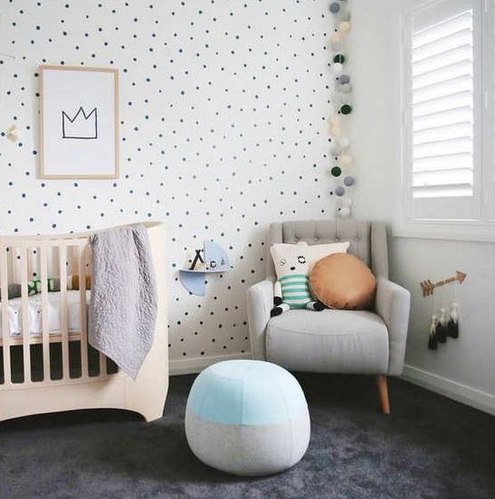 an adorable gender neutral nursery with a spotted wall, a light garland, pastel pillows and cushions