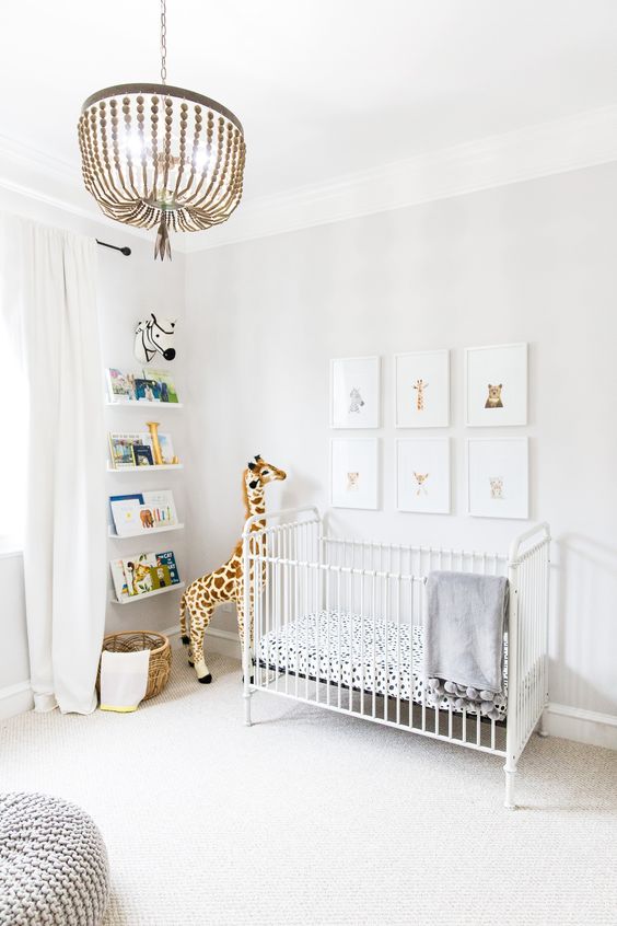 an airy contemporary nursery with a gallery wall, a white crib, a grey chunky knit ottoman and open shelves