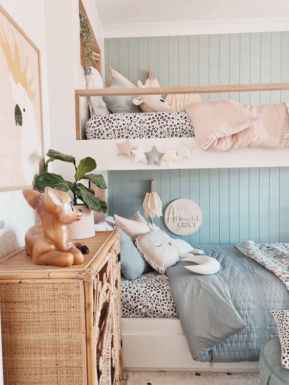 an amazing shared girls' bedroom with a blue accent wall, a bunk bed with blue and pink bedding, a woven storage cabinet