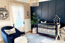 an elegant nursery with a black 3D geometry accent wall, a matching crib and a navy chair to create a cohesive look