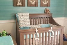 an ocean-themed nursery with reclaimed wood artworks and a turquoise wall and bedding