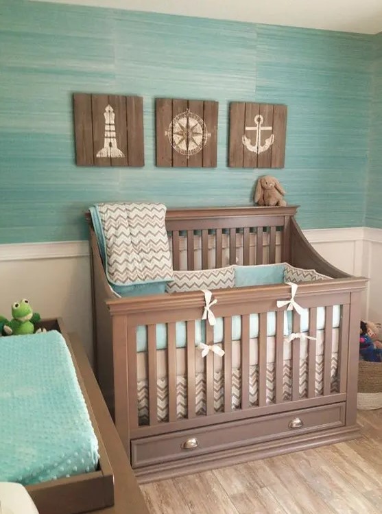 an ocean themed nursery with reclaimed wood artworks and a turquoise wall and bedding