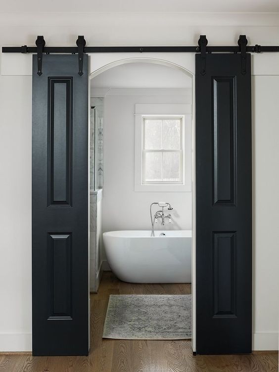 black sliding barn doors contrast the neutral space and hide the entrance to the bathroom