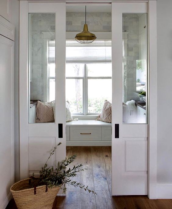 double sliding French doors leading to a cozy and welcoming sunroom done in neutrals