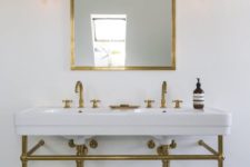 wall-mounted pendant lamps in gold match the vanity and the mirror frame and look chic