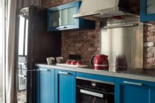 a bold blue kitchen with dark touches and a red brick kitchen backsplash plus shiny metal touches