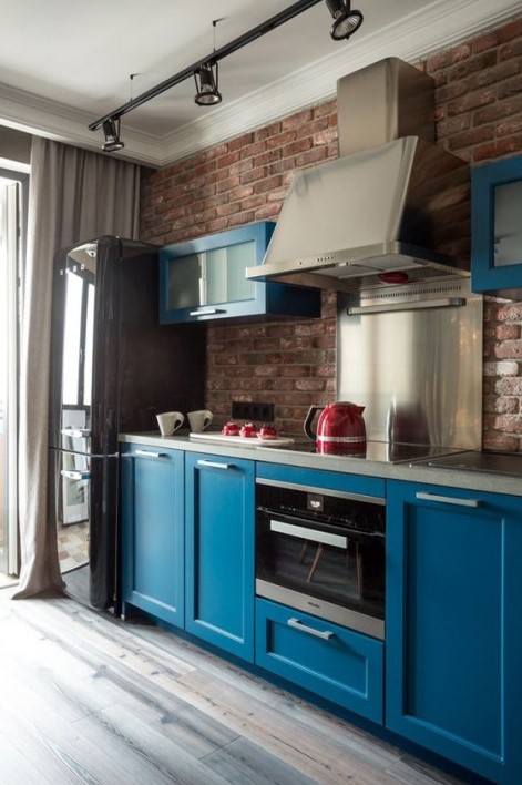 a bold blue kitchen with dark touches and a red brick kitchen backsplash plus shiny metal touches