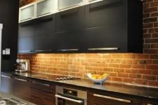 a red brick wall adds texture and color to the space and contrasts the sleek cabinets