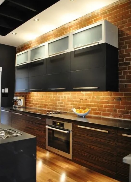 a red brick wall adds texture and color to the space and contrasts the sleek cabinets