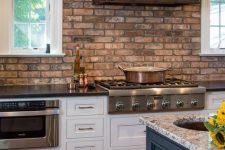 a shabby red birck wall and a darkened metal hood add interest to the space and stone countertops match