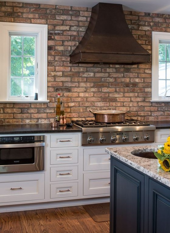 a shabby red birck wall and a darkened metal hood add interest to the space and stone countertops match