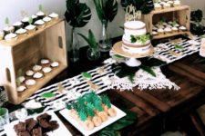 a tropical dessert table done in black and white with touches of green, with stripes, tropical leaves and delicious sweets