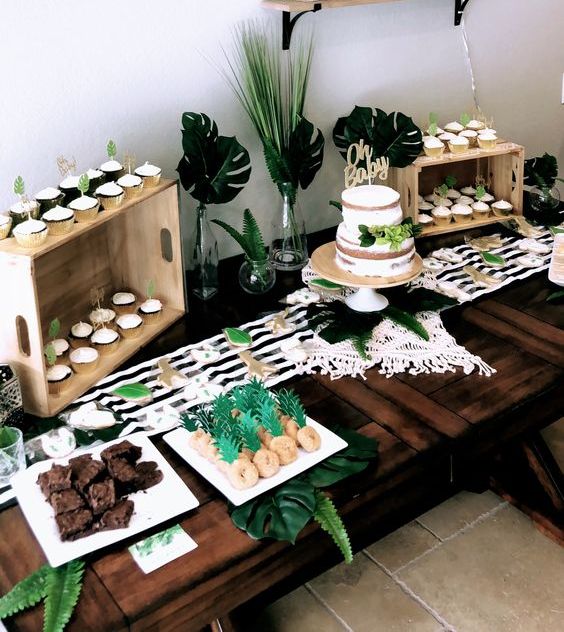 a tropical dessert table done in black and white with touches of green, with stripes, tropical leaves and delicious sweets
