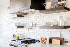 a vintage kitchen with white cabinets, copper hardware and a white faux brick wall that makes the hood stand out