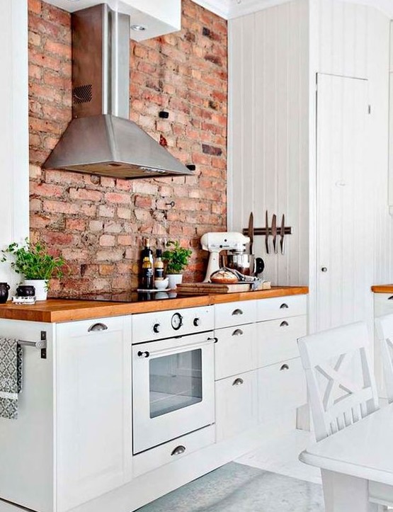 a welcoming modern farmhouse kitchen with white cabinets, rich stained countertops and a red brick wall