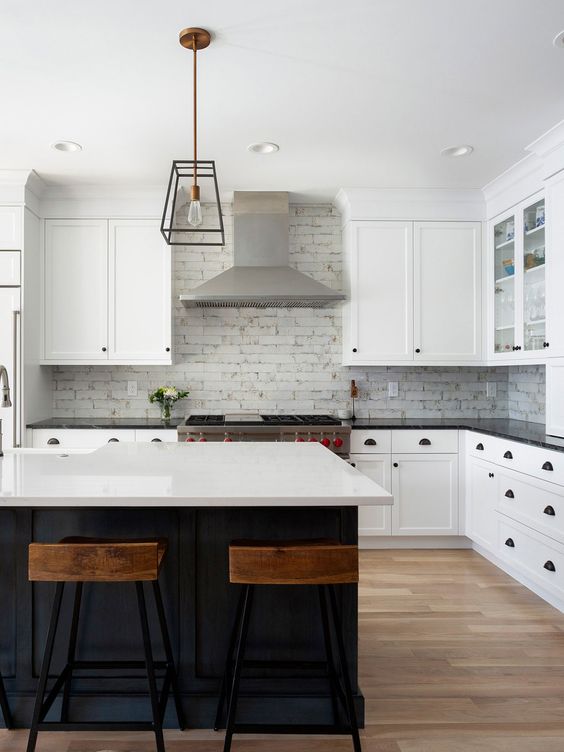 a white farmhouse kitchen with shaker style cabinets, a white brick backsplash, glass cabinets and stainless steel appliances