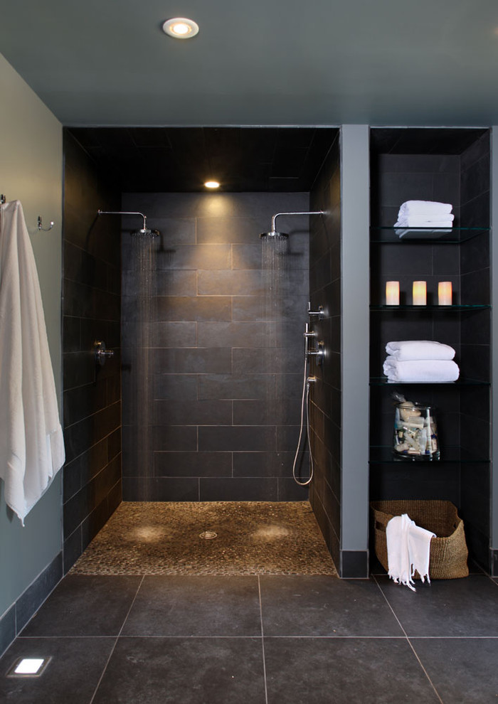 Dark gray, industrial-inspired stone tiles look great in an open shower. A pebble tile flooring is comfy to walk on. (NF interiors)