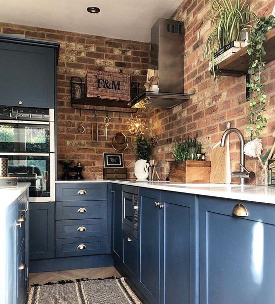 blue kitchen cabinets with white countertops and red brick walls is a bold contrasting idea with a touch of chic