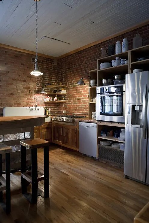 red brick walls match the rich stained wood and add texture and interest to the kitchen