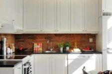 vintage white cabinets and red bricks contrast with each other and add texture to the kitchen