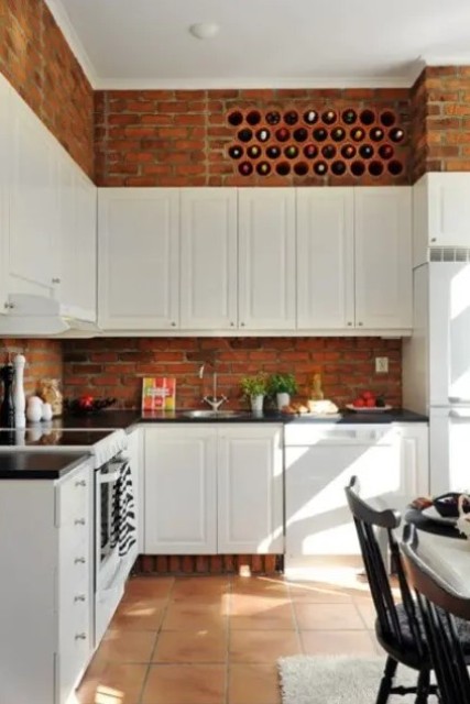 vintage white cabinets and red bricks contrast with each other and add texture to the kitchen