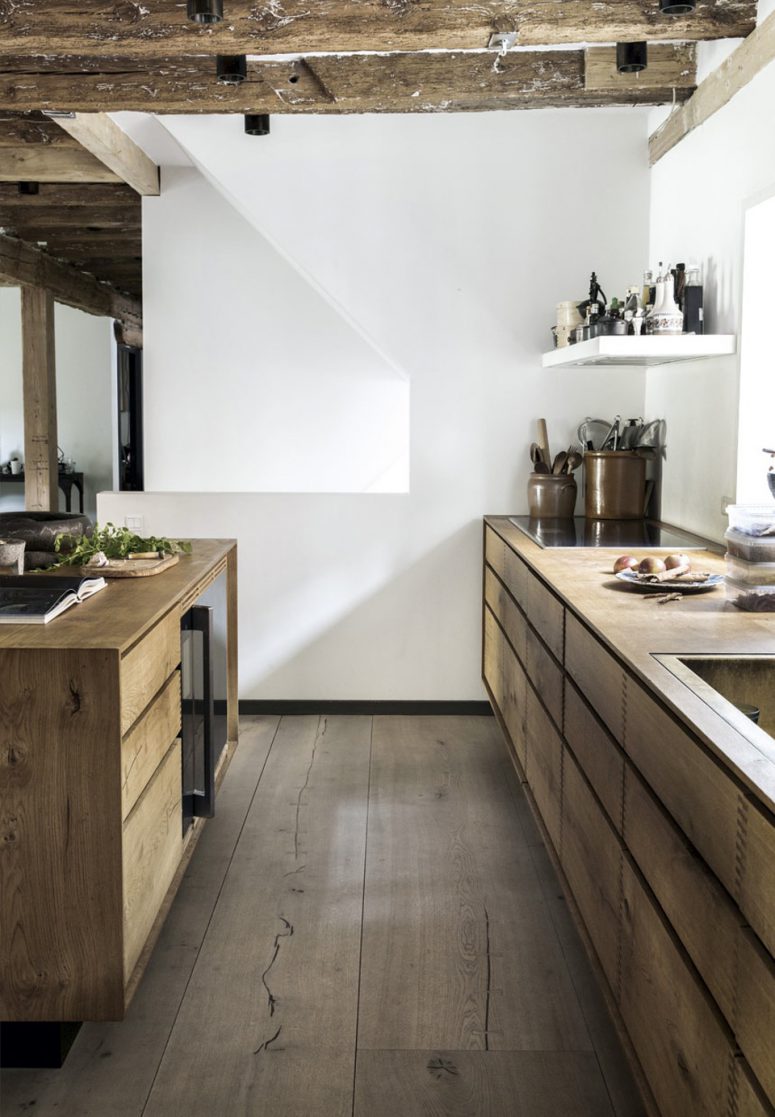 The kitchen with exposed wooden beams looks modern and comfy but with a rustic vibe