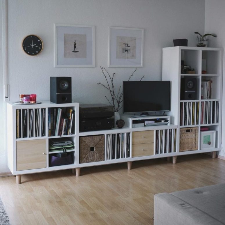 a storage and TV unit built of several IKEA Kallax pieces, placed on wooden legs and with drawers and boxes to make it as practical as possible